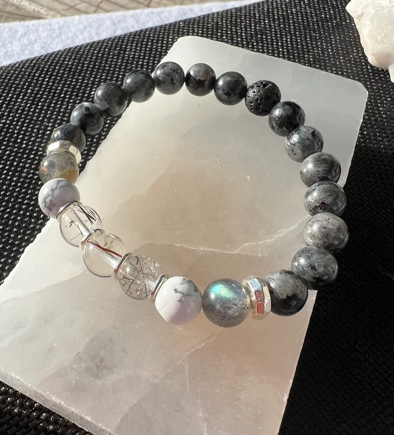 labradorite gemstone bracelet sitting on a smooth white stone 